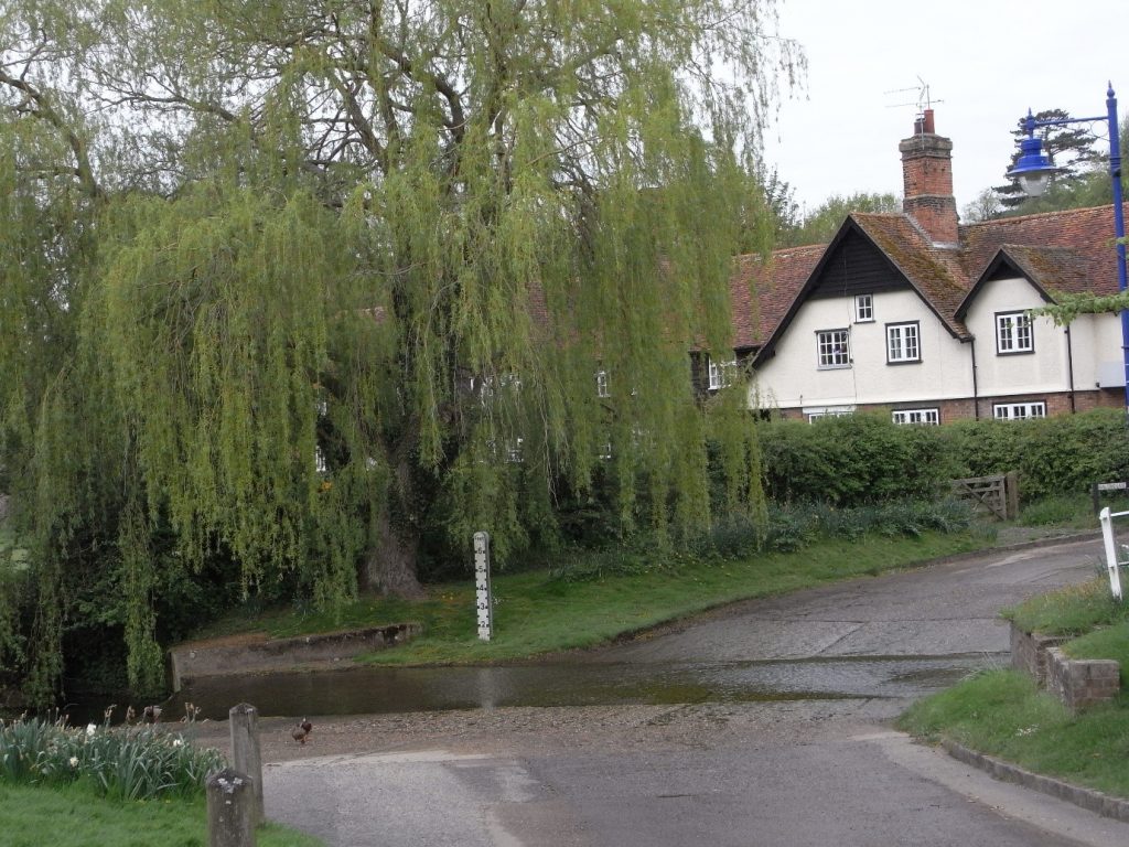 A house at a crossroads with a weeping willow tree infront of the house