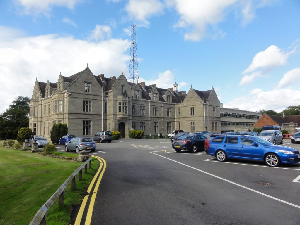 A large house with a car park in front of it
